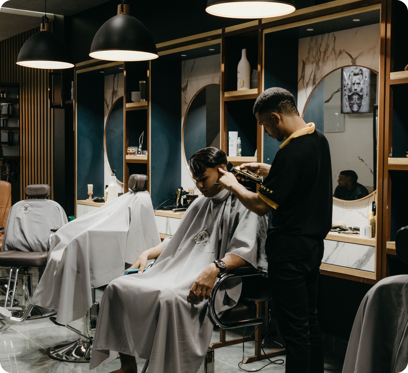 A barber finishing a client's cut in a fitted-out shop