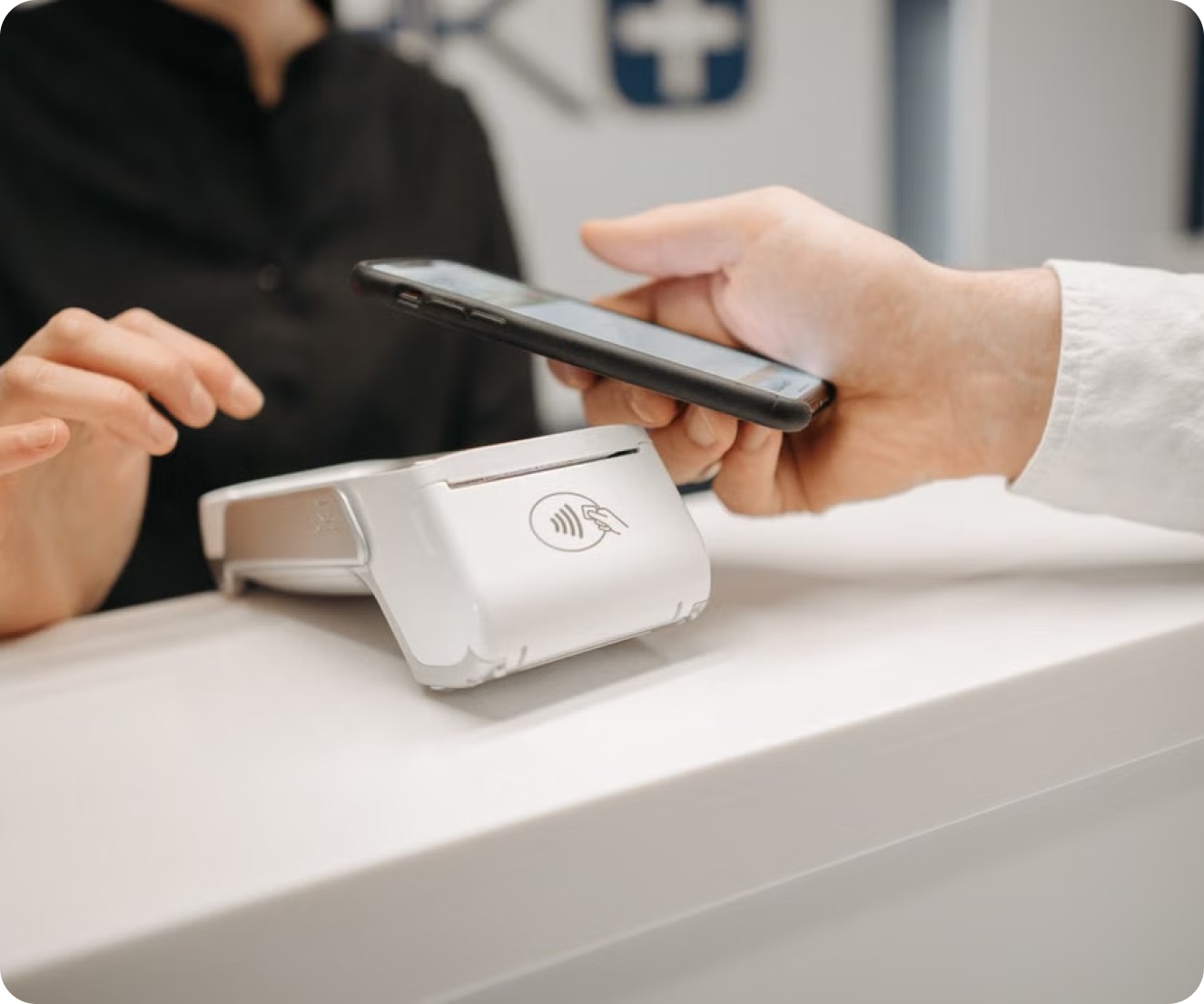 A client tapping a phone against a card reader at the front desk