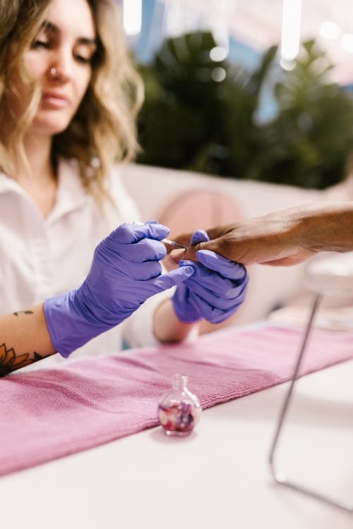 A nail technician finishing a client's manicure